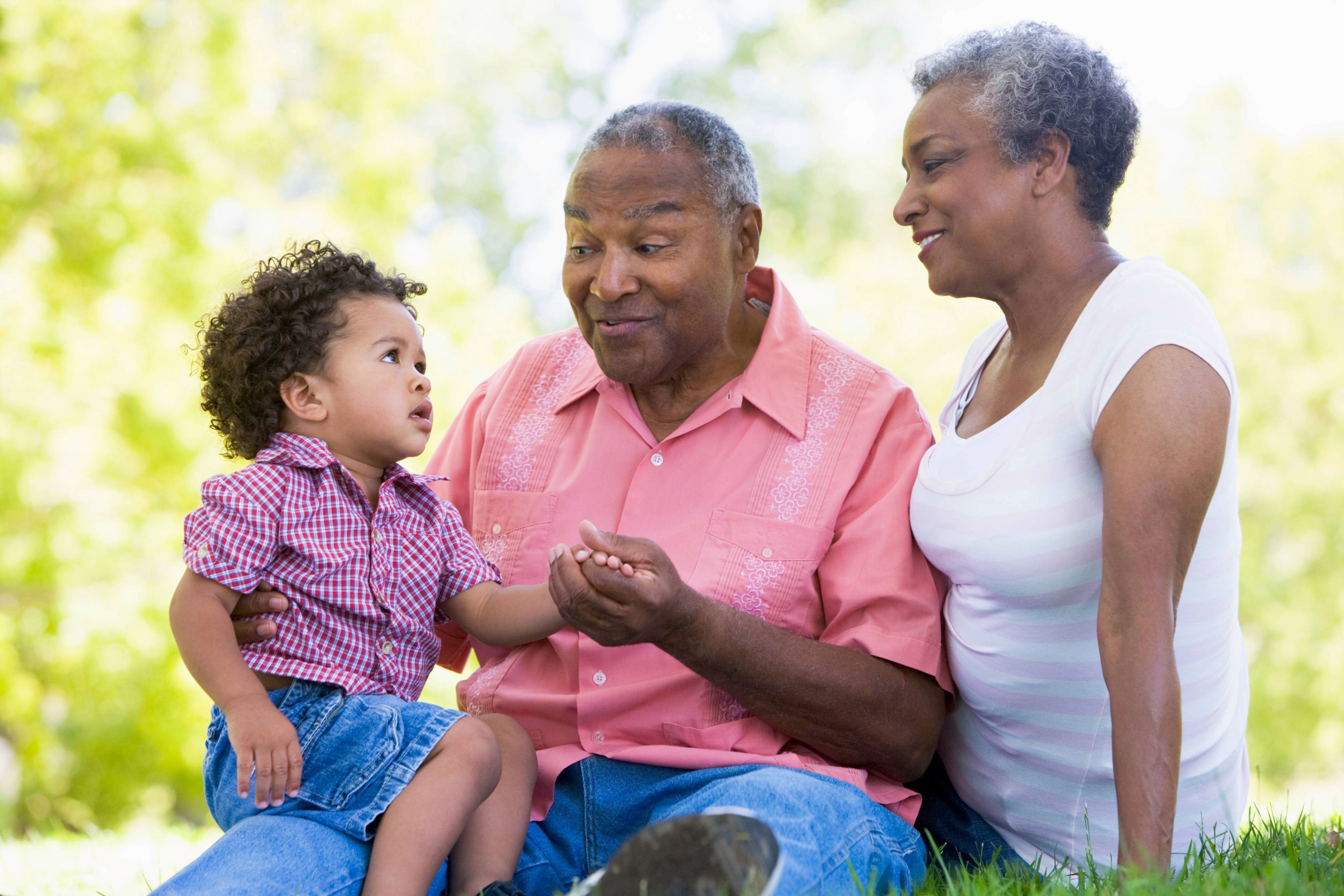 Image of grandmother, grandfather, and grandchild sitting outside together